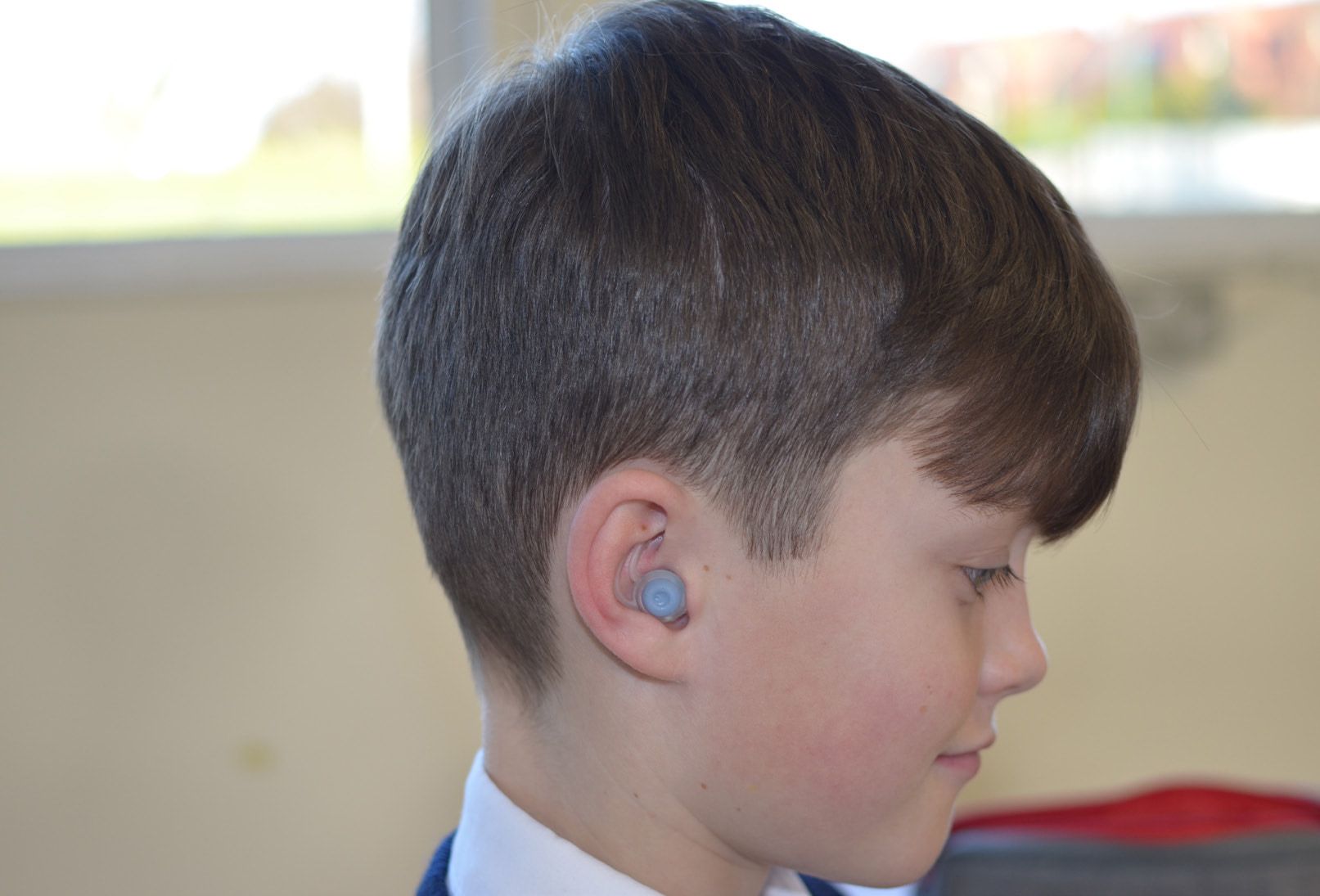 Our test user in profile, smiling, wearing the prototype earbud.